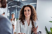 Waist up shot of beautiful young woman shaking hand to stylish businessman in office setting