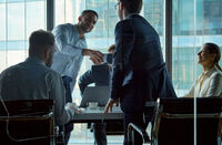 Young business negotiators shaking hands with partners after closing a deal in a modern office building