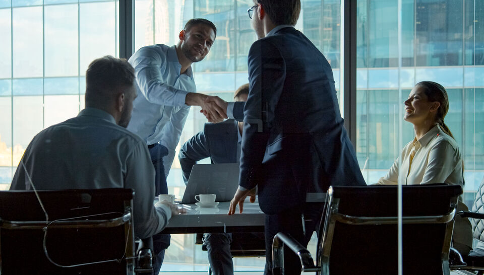 Young business negotiators shaking hands with partners after closing a deal in a modern office building